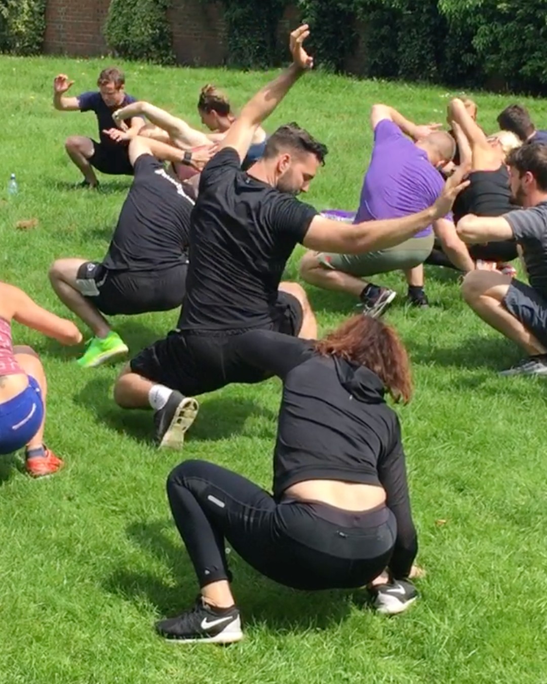 A big mixed class on the grass, squatting and crawling